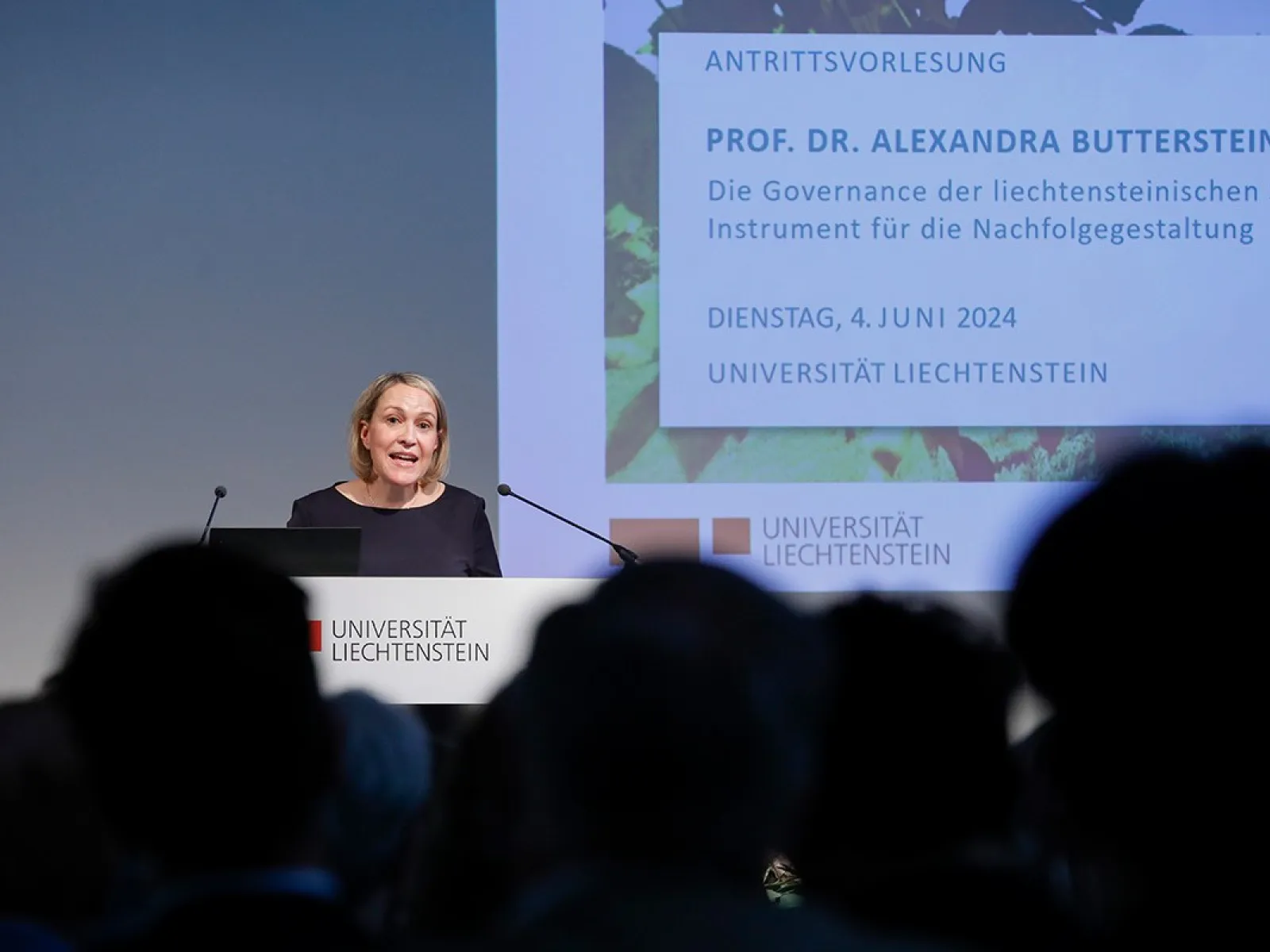 Eine Person hält eine Antrittsvorlesung im Auditorium der Universität Liechtenstein. Im Hintergrund ist eine Präsentationsfolie mit dem Titel der Vorlesung und dem Datum zu sehen. Das Publikum sitzt im Vordergrund.