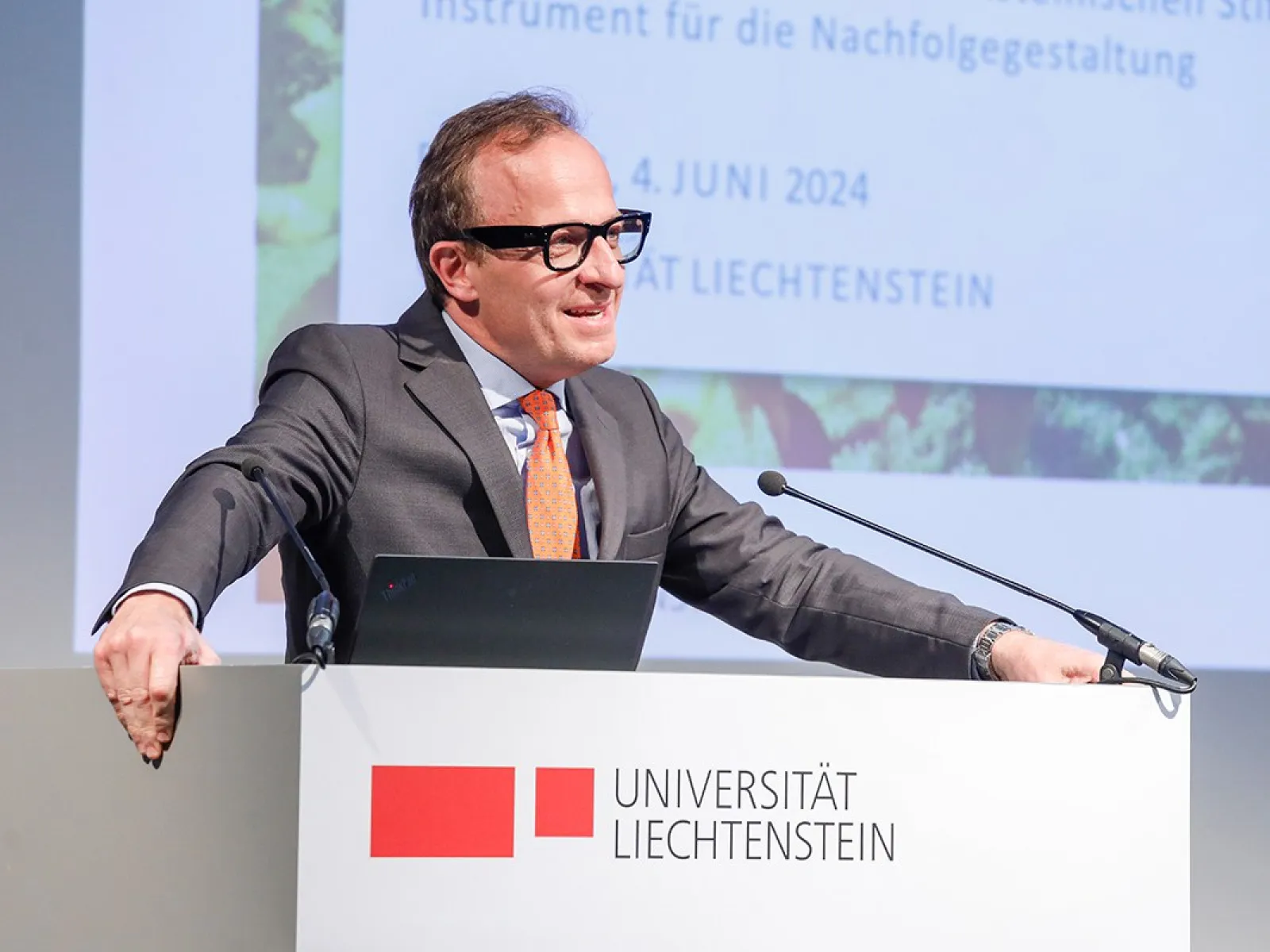 Ein Redner steht an einem Podium der Universität Liechtenstein und hält eine Präsentation. Im Hintergrund ist ein Bildschirm mit dem Datum 4. Juni 2024 zu sehen.