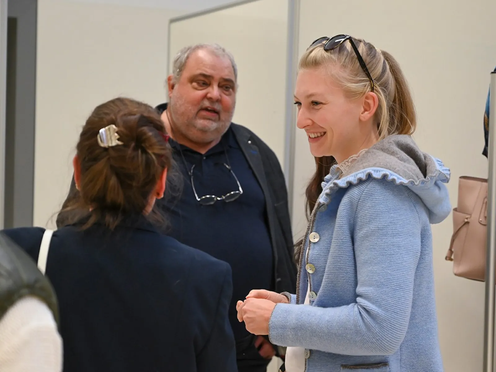 Eine Gruppe von Personen unterhält sich in einem hellen Raum während der Erasmus-Days an der Universität Liechtenstein. Eine Frau im Vordergrund trägt eine blaue Jacke und lächelt.