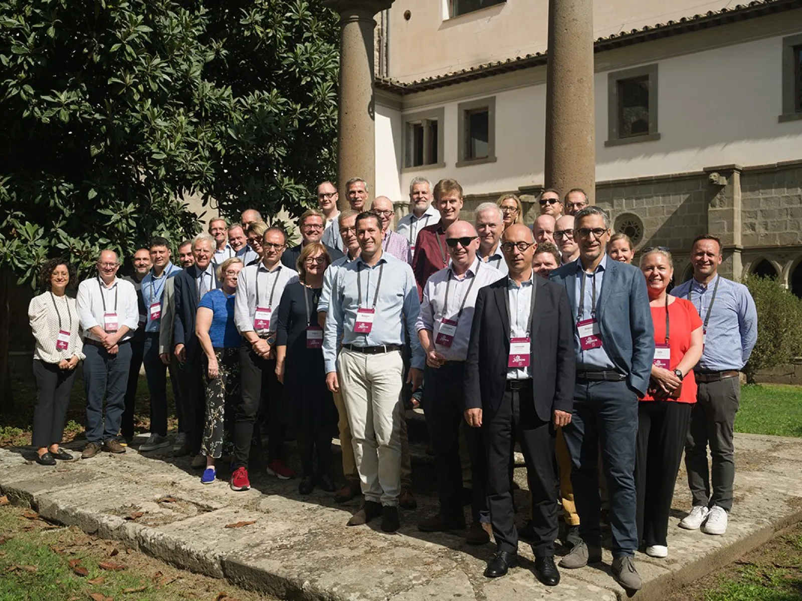Gruppe von Menschen steht draußen vor einem historischen Gebäude während des ERCIS-Workshops in Viterbo, Italien. Sie tragen Namensschilder und lächeln in die Kamera.