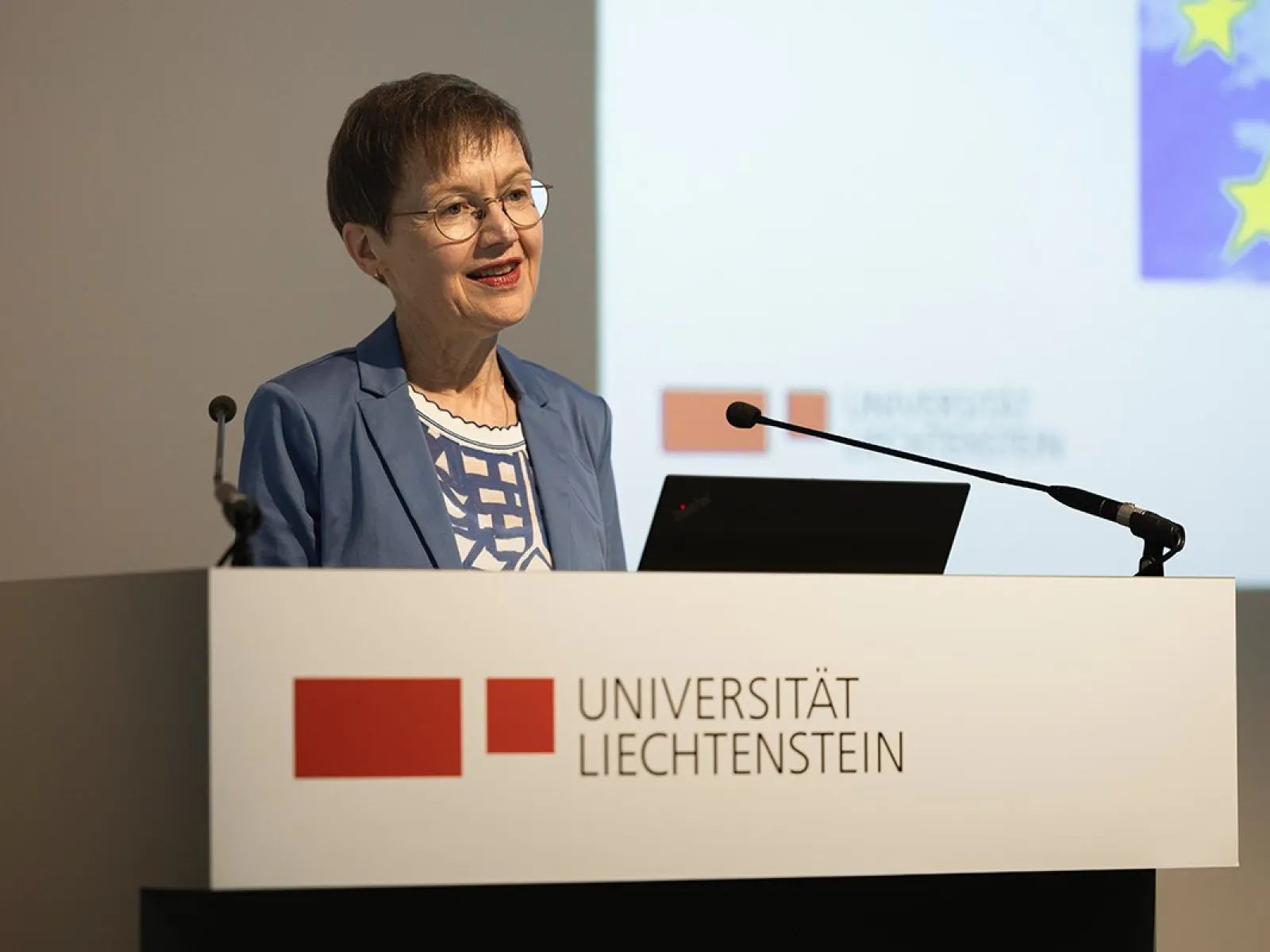 Eine Frau steht am Rednerpult im Auditorium der Universität Liechtenstein. Vor ihr steht ein Laptop, hinter ihr ist eine Präsentation zu sehen.