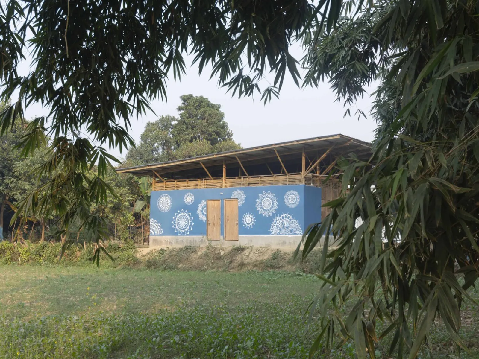 Ein nachhaltiges Gebäude mit blauer Fassade und weißen Mustern, umgeben von grüner Vegetation, symbolisiert umweltfreundliche Architektur.
