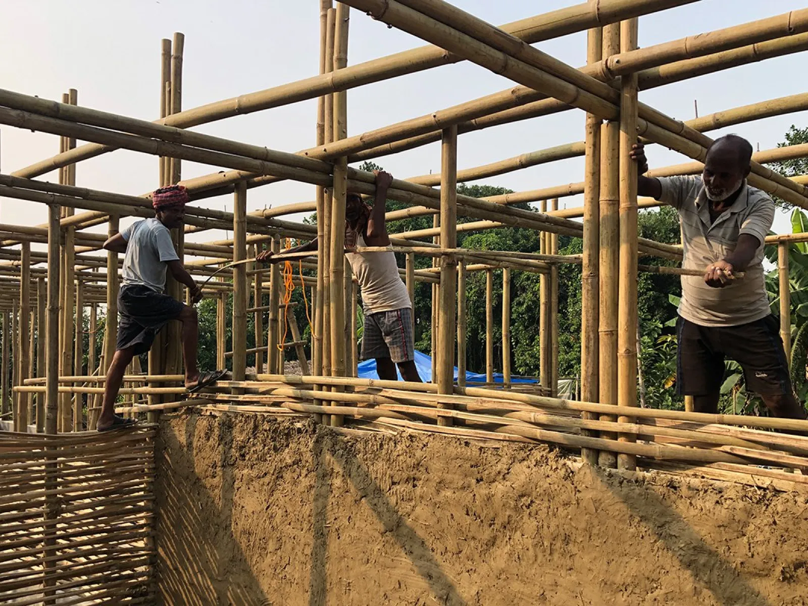 Arbeiter errichten eine Schule in Bahuarwa, Indien, mit Bambusgerüst und Lehmwänden. Das Projekt wird von der Universität Liechtenstein unterstützt.