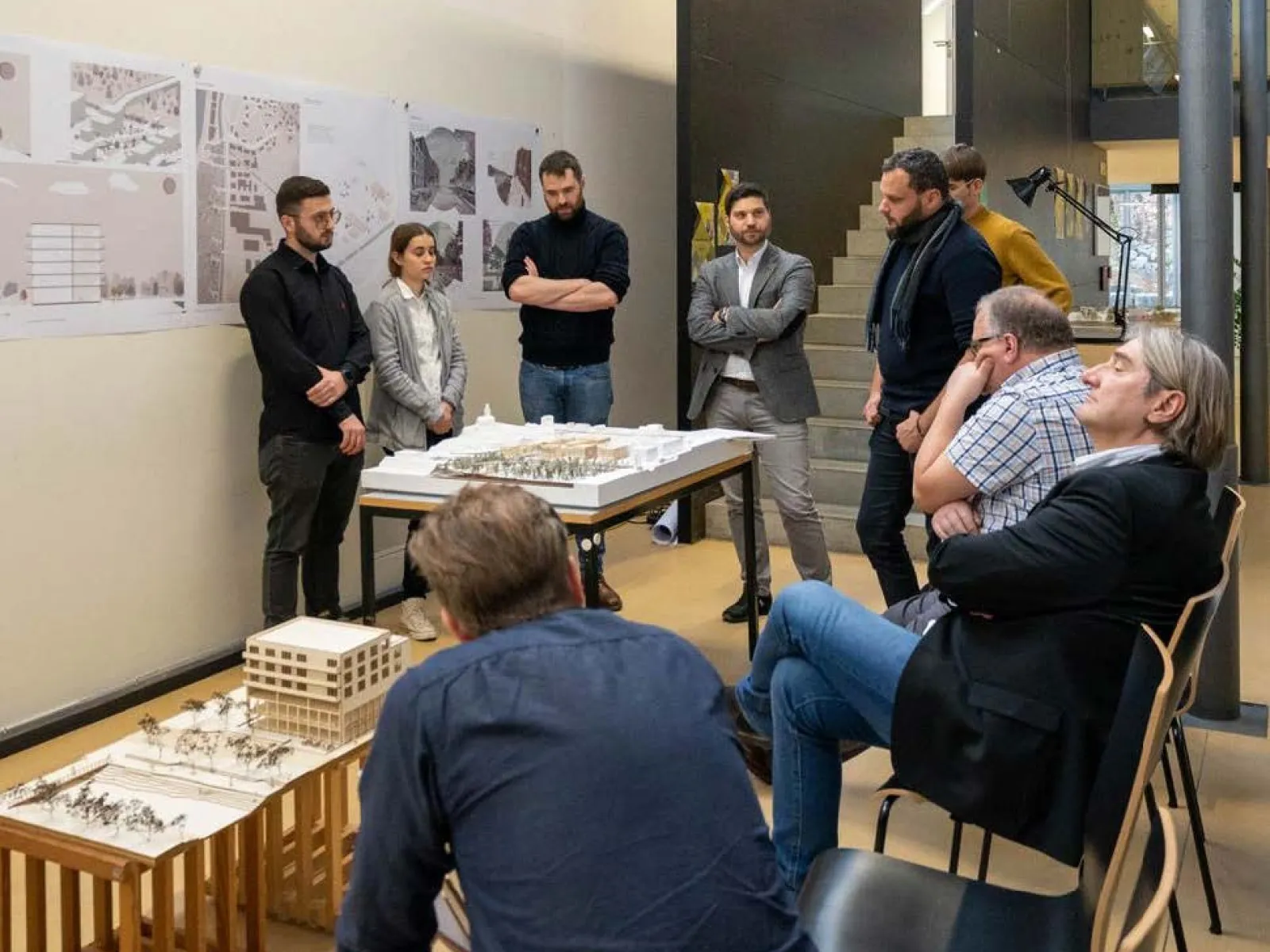 Mehrere Menschen bei einer Präsentation von Studierenden mit einem Architekturmodell