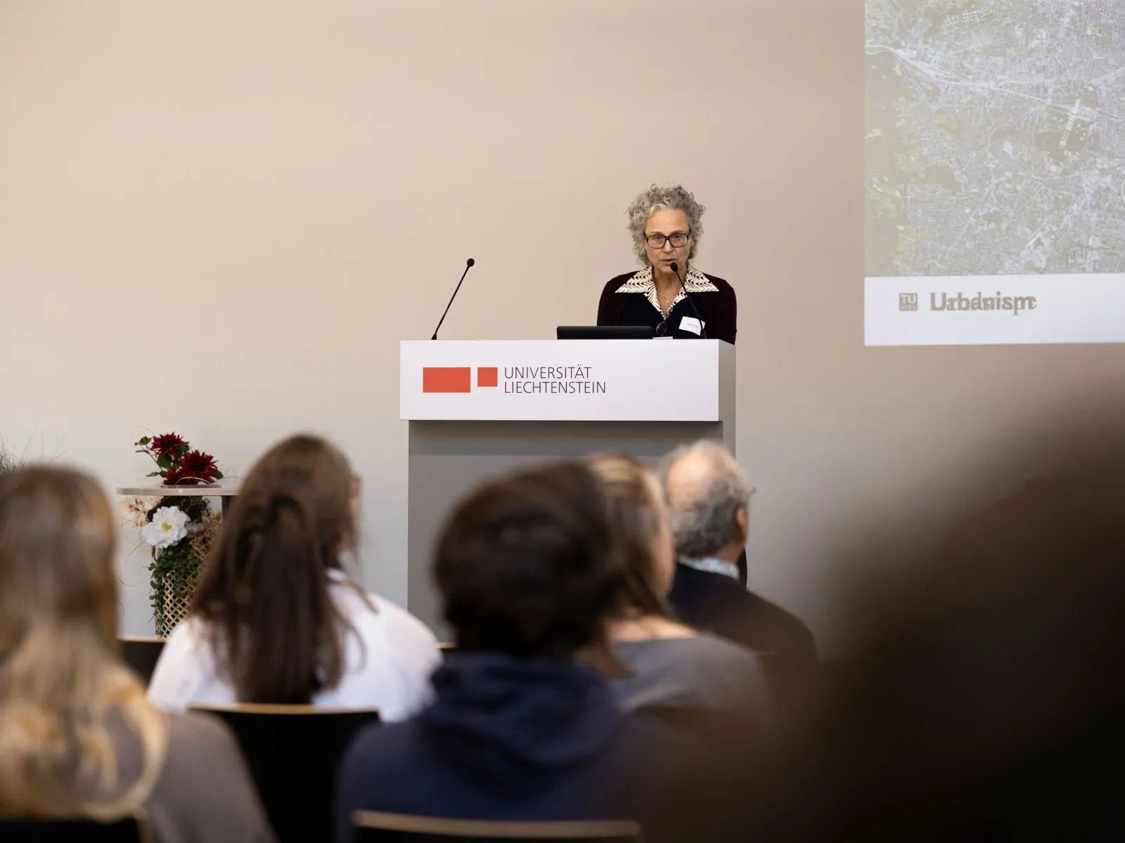 Frau mit Brille und Mikrofon bei einem Vortrag
