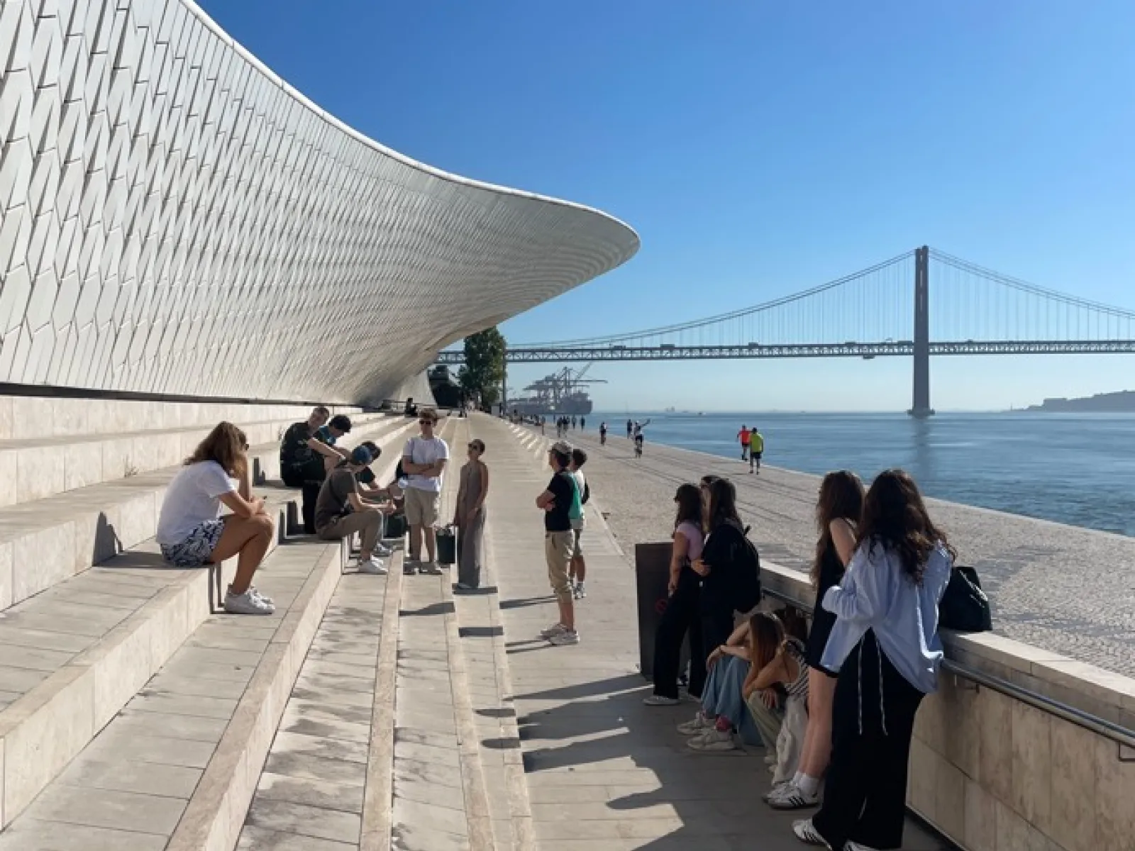 Gruppe junger Menschen sitzen auf Stufen vor einer Brücke