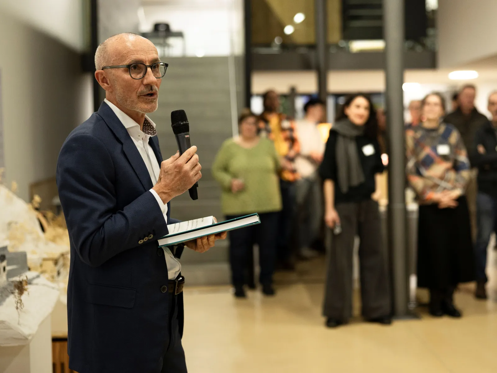 Ein Mann präsentiert vor einer Gruppe von Menschen mit einem Mikrofon in der Hand