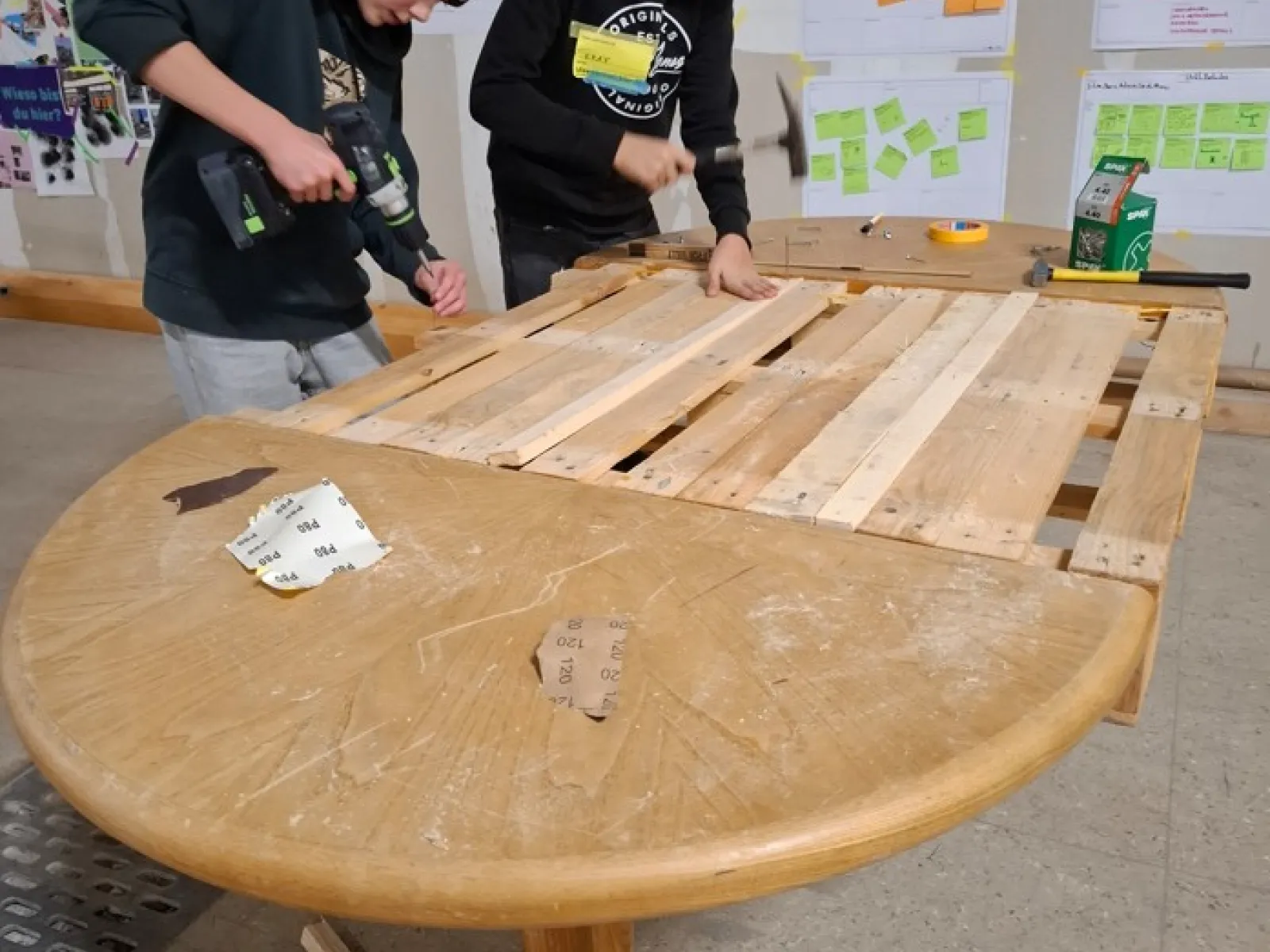 Zwei Jugendliche arbeiten an einem Holztisch
