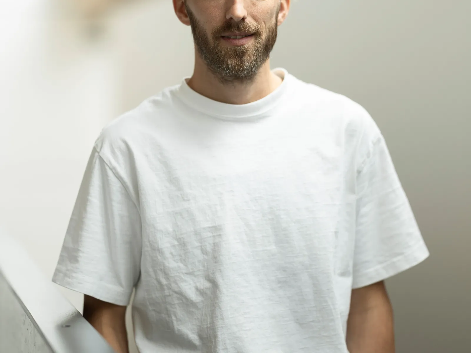 Foto eines jungen Mannes mit weissem T-Shirt und Bart