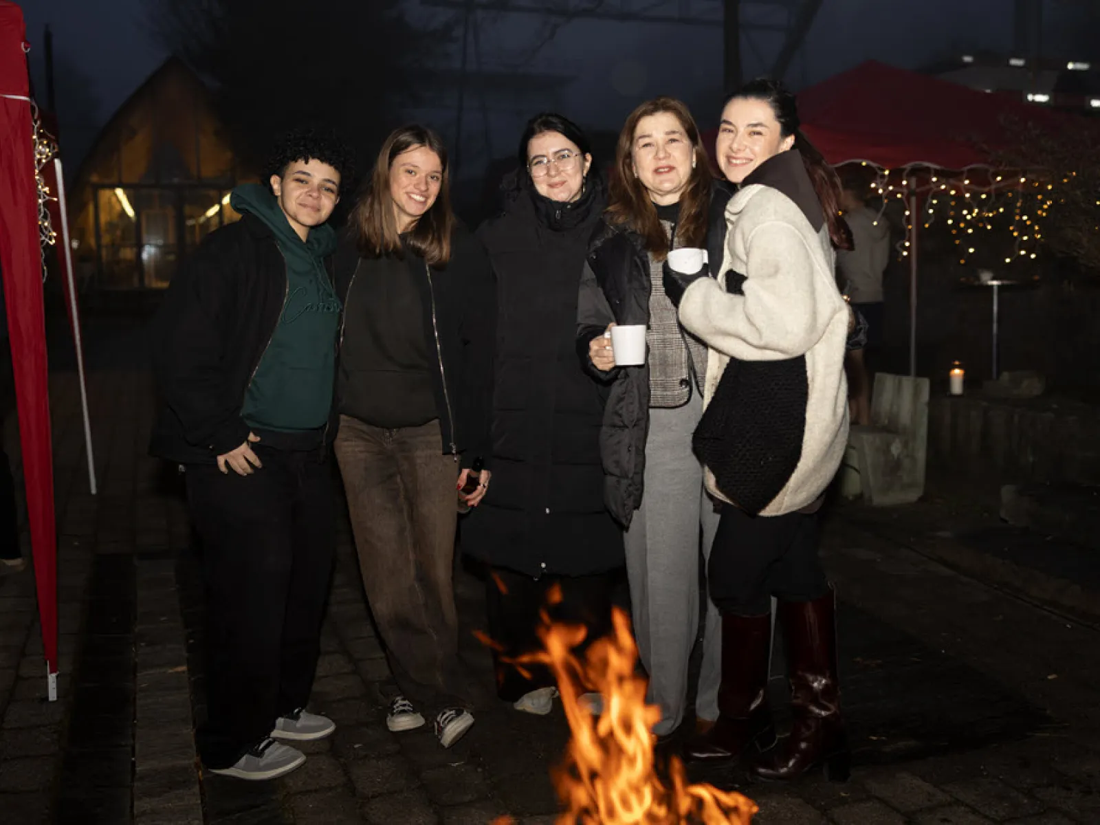 Studierende wärmen sich an der Feuerschale.