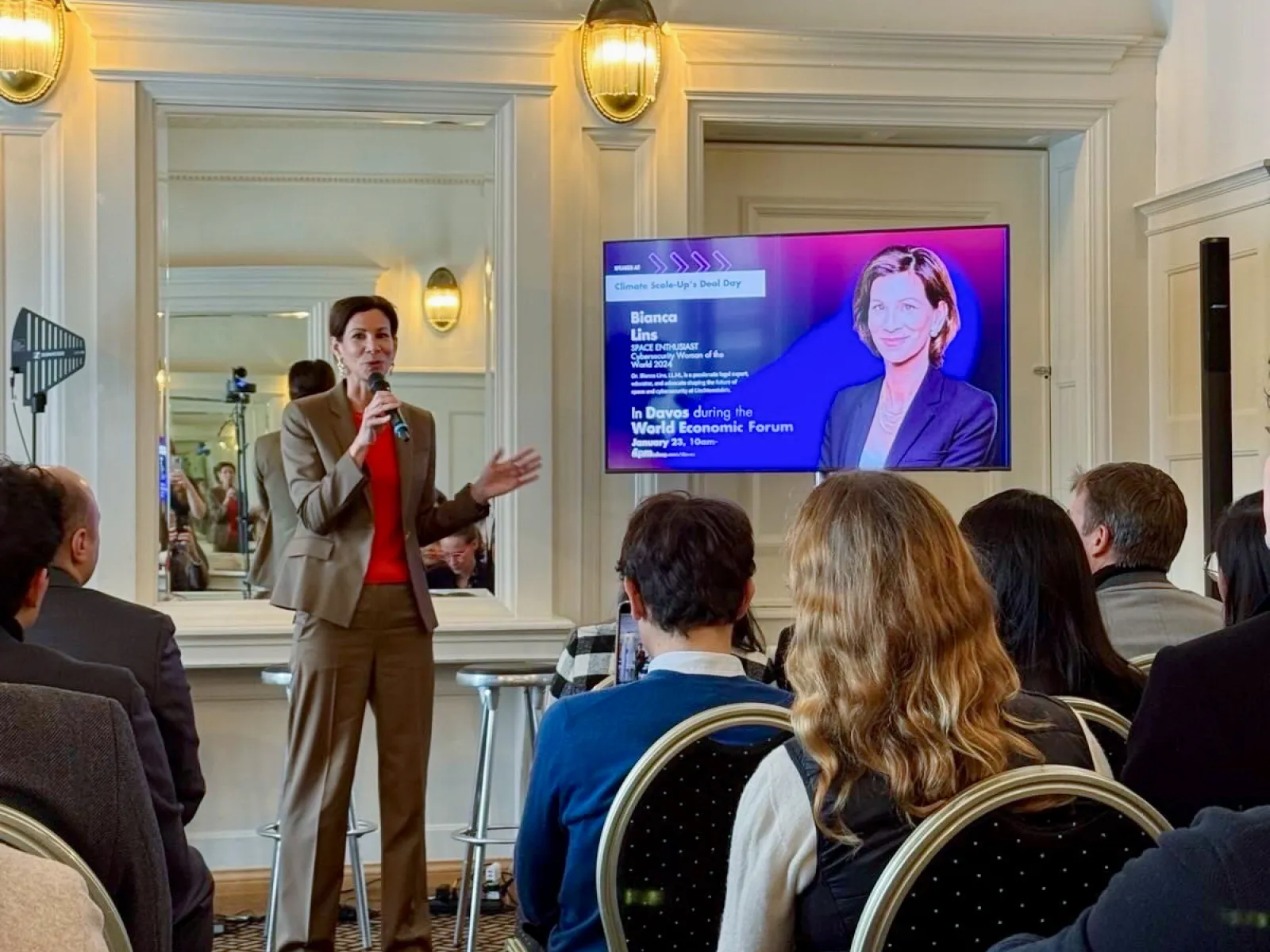 Referentin spricht vor Publikum bei Netzwerkveranstaltung mit Bildschirmpräsentation im Hintergrund