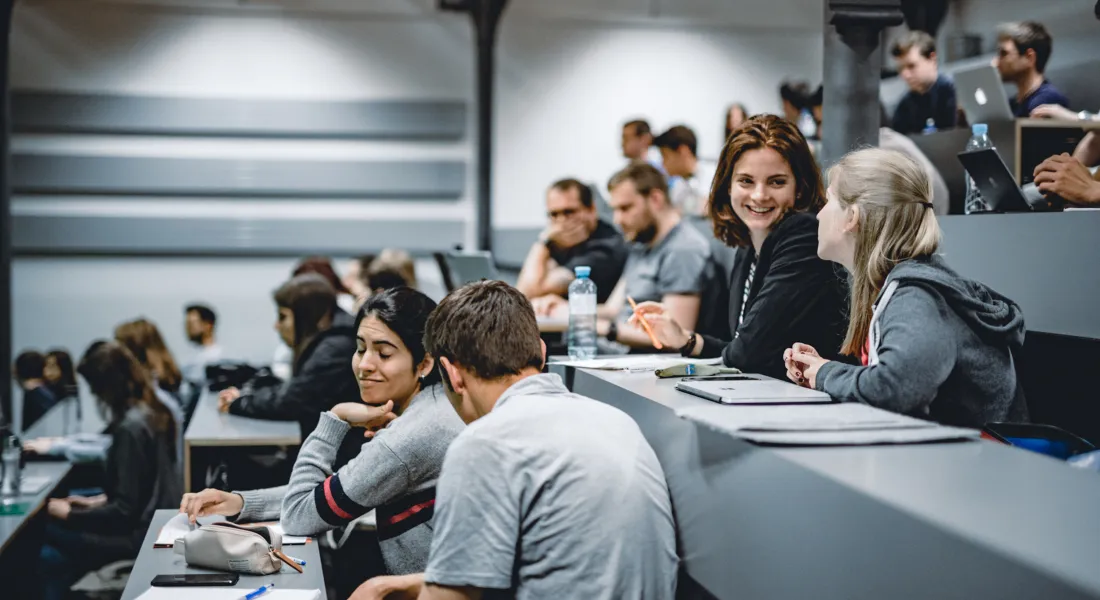 Studierende der Universität Liechtenstein sitzen im Hörsaal und unterhalten sich vor Beginn einer Vorlesung.