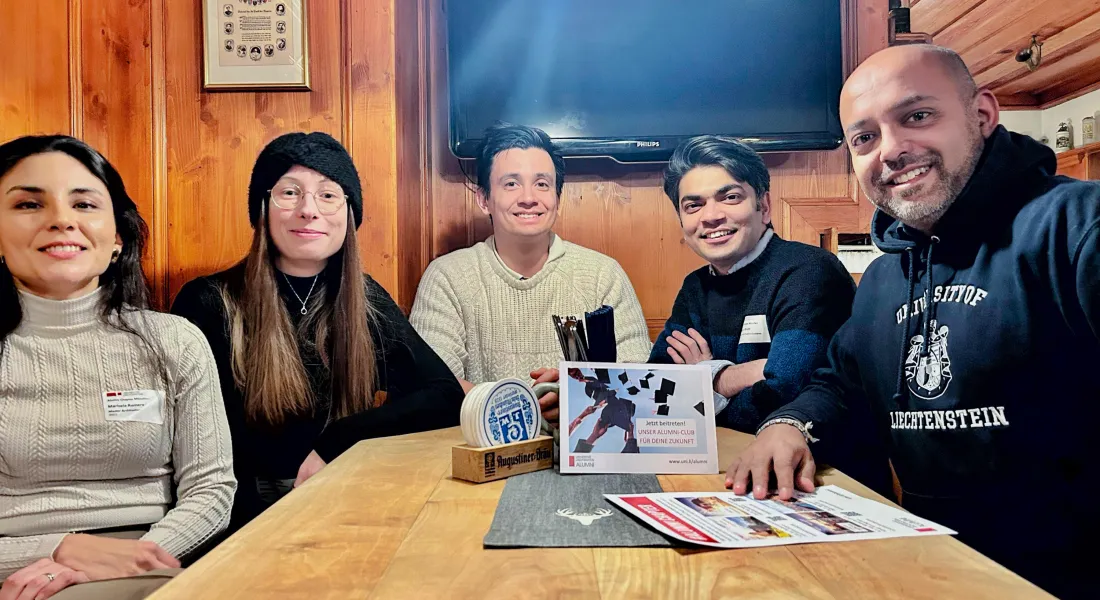 Sechs Alumni der Universität Liechtenstein sitzen an einem Holztisch und sprechen über den Alumni Club.