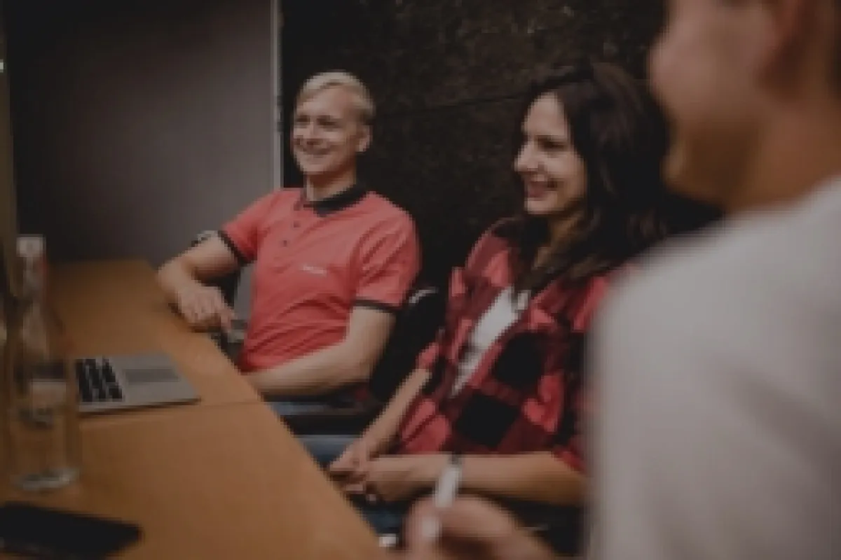 Gruppe von vier Personen sitzt an einem Tisch mit dem Schriftzug "Für Unternehmen".