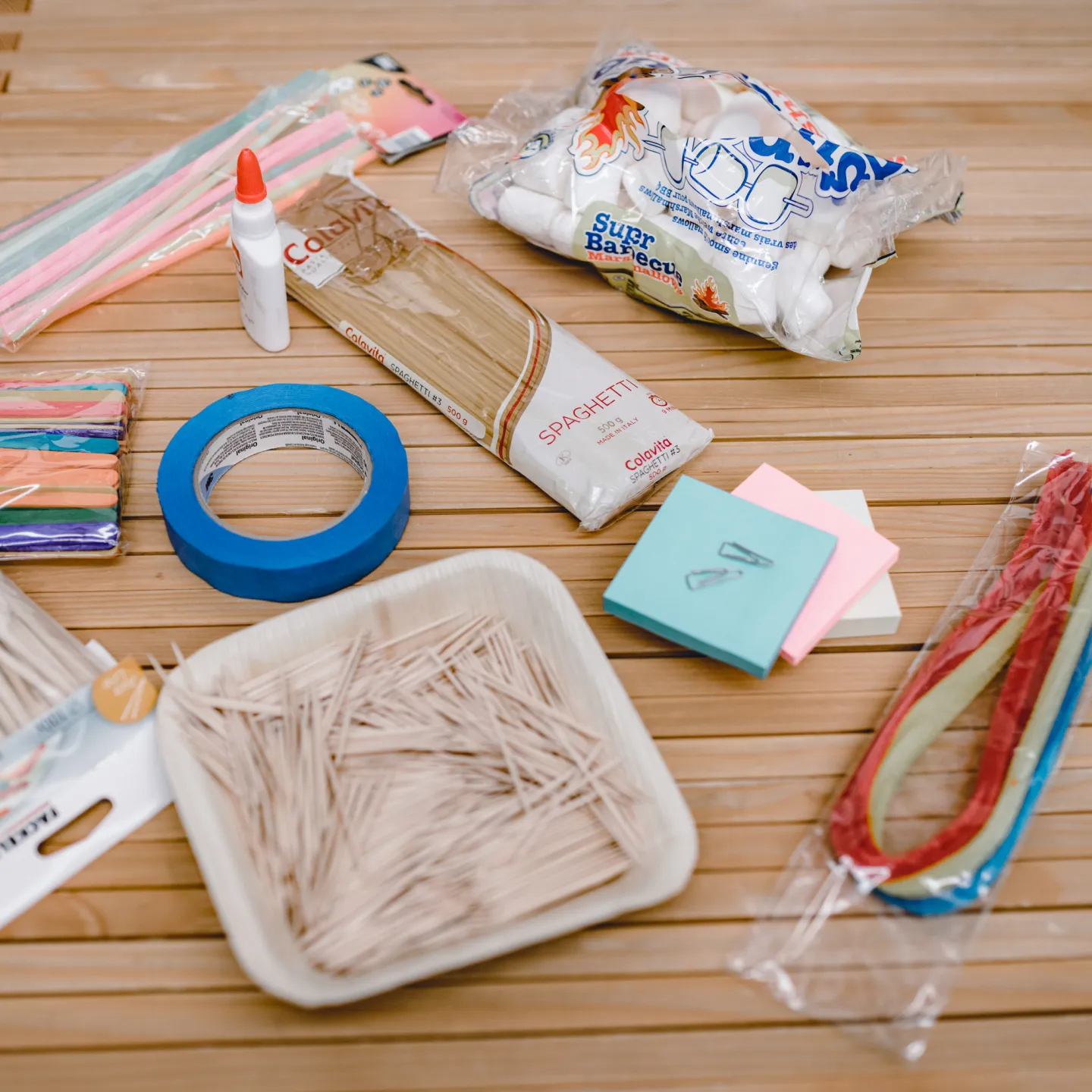 Bastelmaterialien auf Holztisch: Spaghetti, Kleber, Marshmallows und bunte Werkstoffe – Workshop an der Universität Liechtenstein
