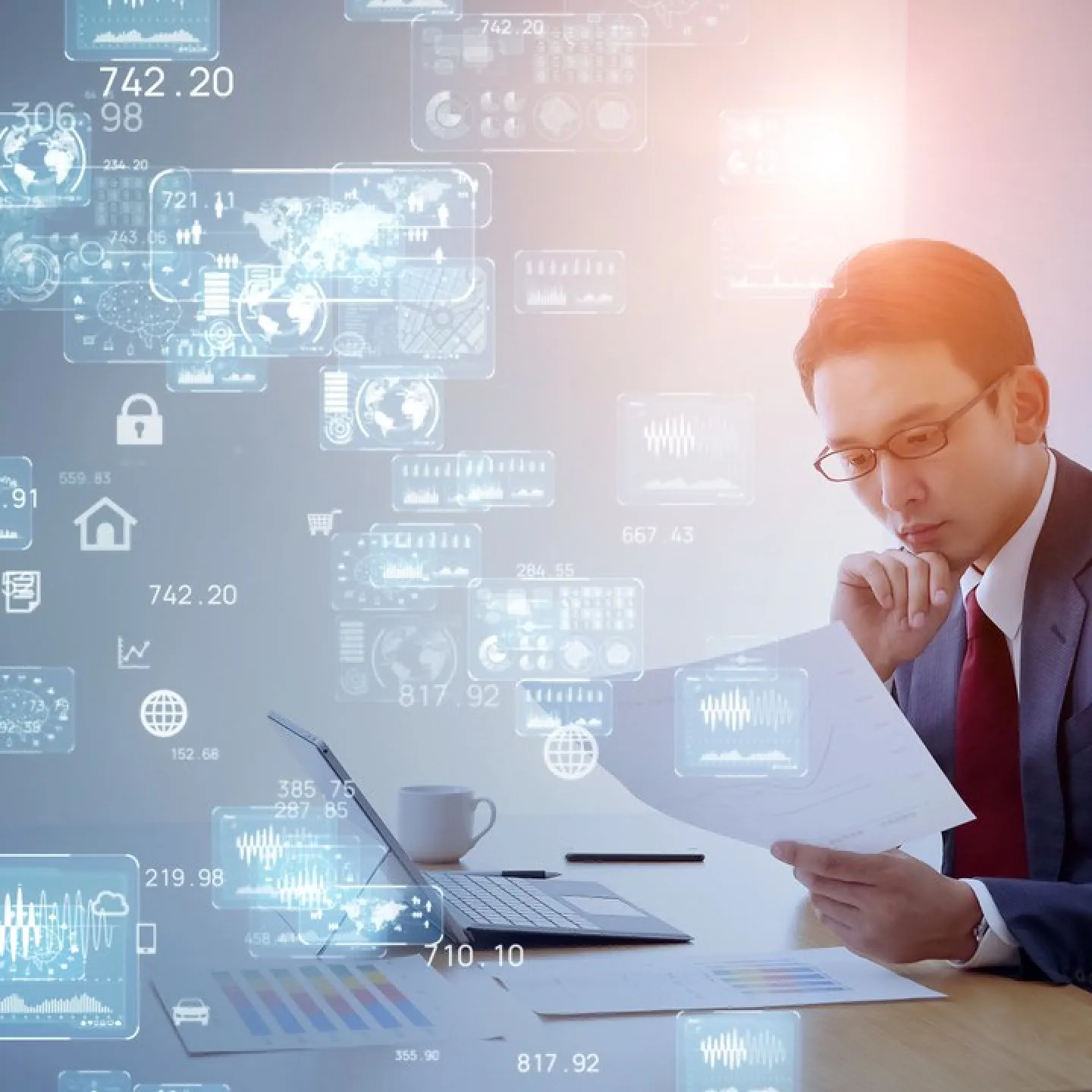 Ein Mann im Anzug sitzt an einem Schreibtisch und betrachtet konzentriert Dokumente. Vor ihm steht ein Laptop, umgeben von digitalen Grafiken und Datenvisualisierungen, die den digitalen Wandel symbolisieren.