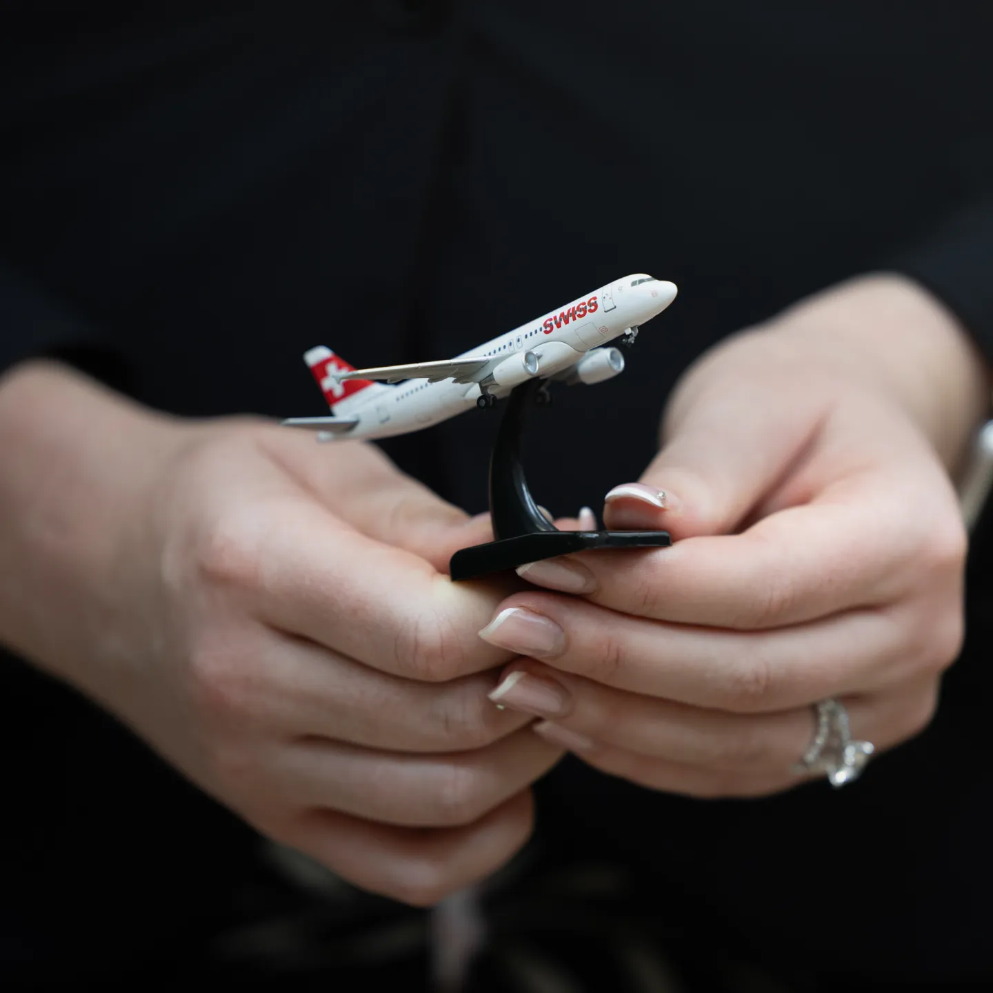 Hände halten Modellflugzeug der Fluggesellschaft SWISS.
