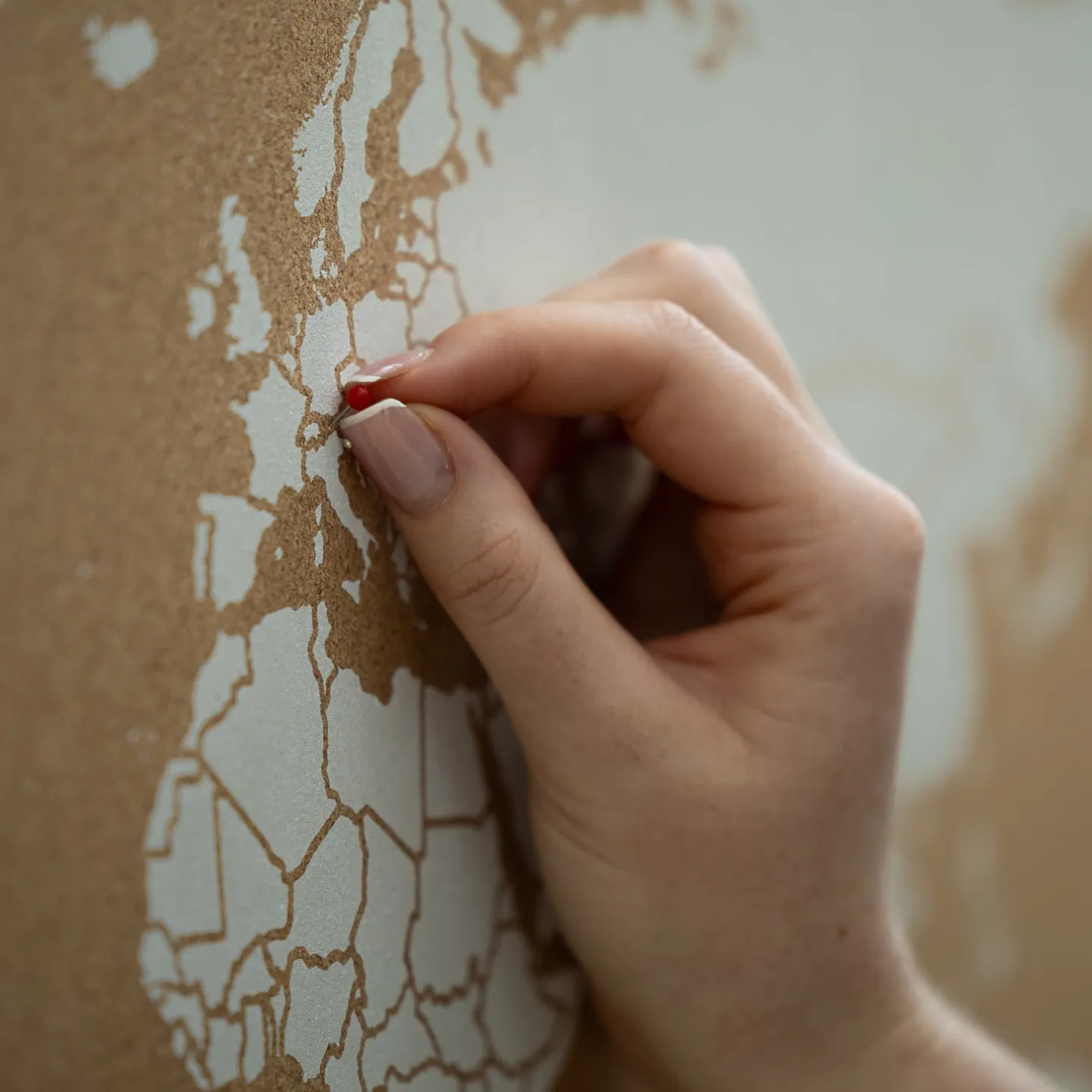 Hand steckt roten Pin in Europakarte zur Markierung eines Ortes.