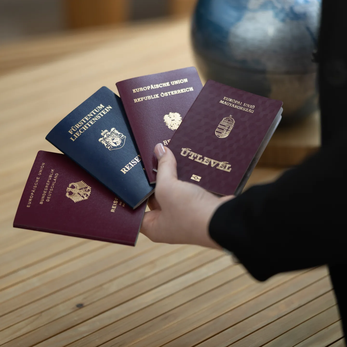 Hand hält mehrere europäische Reisepässe verschiedener Länder.