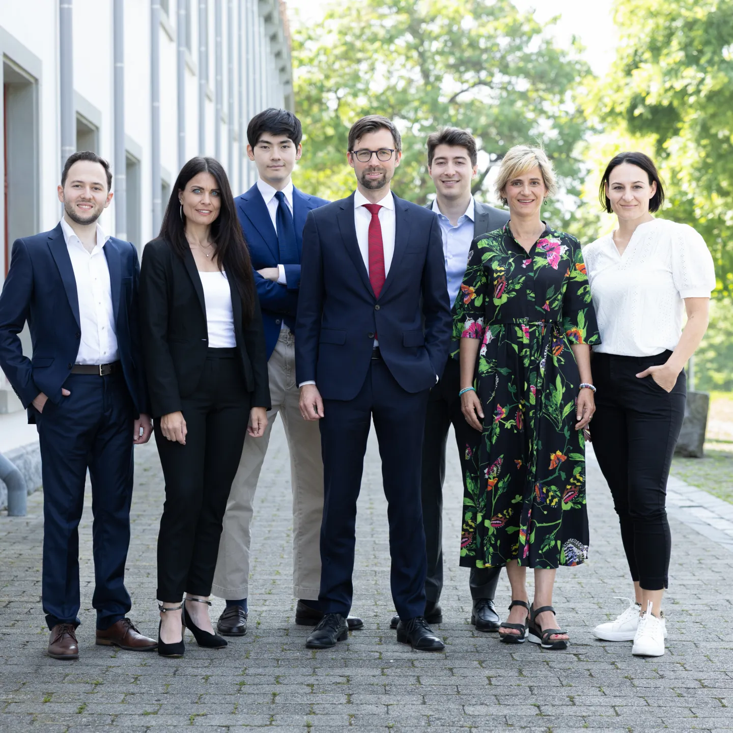 Gruppe von sieben Personen in Businesskleidung vor dem Gebäude der Universität Liechtenstein.