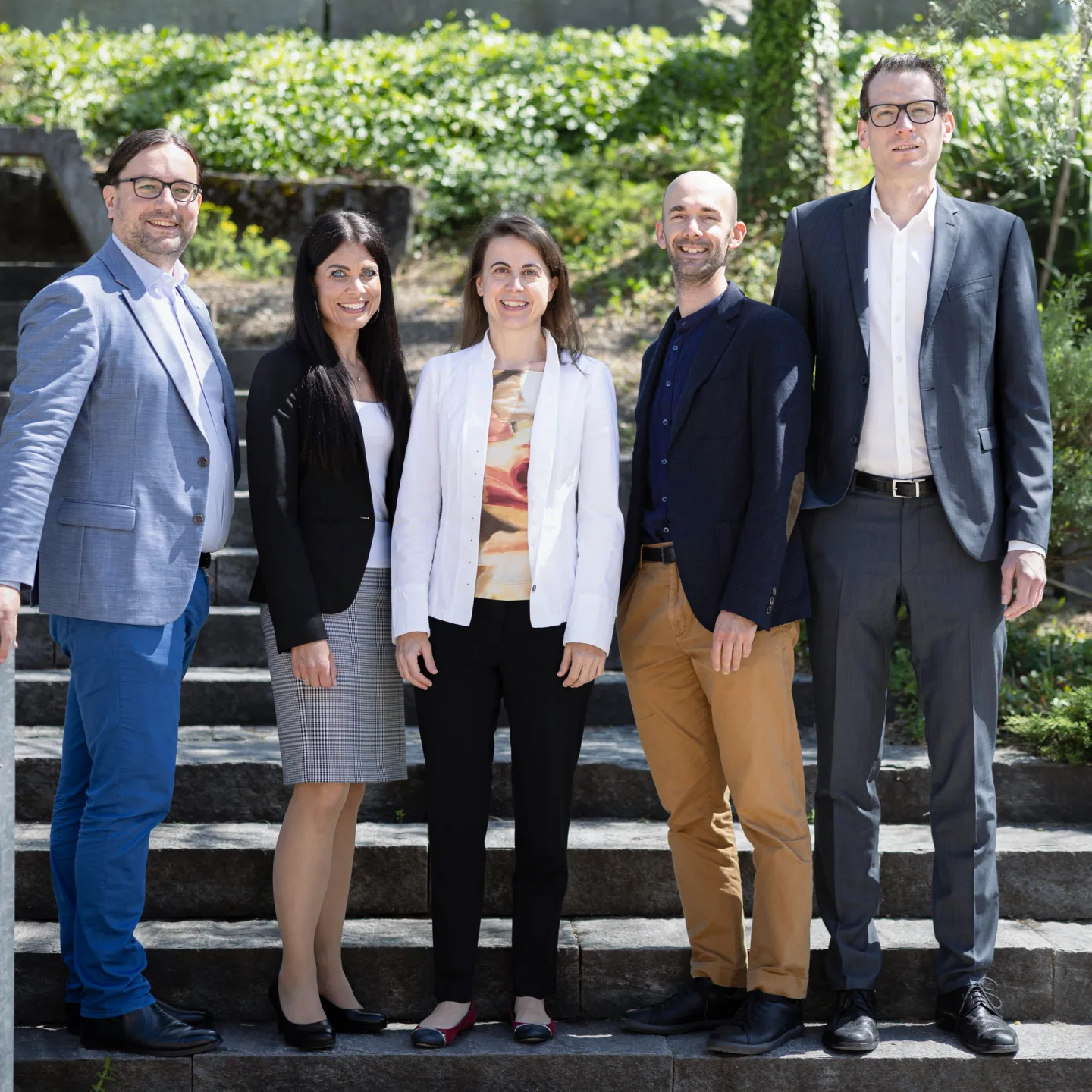 Dozierende und Mitarbeitende der Business School der Universität Liechtenstein posieren gemeinsam für ein Gruppenfoto im Freien.