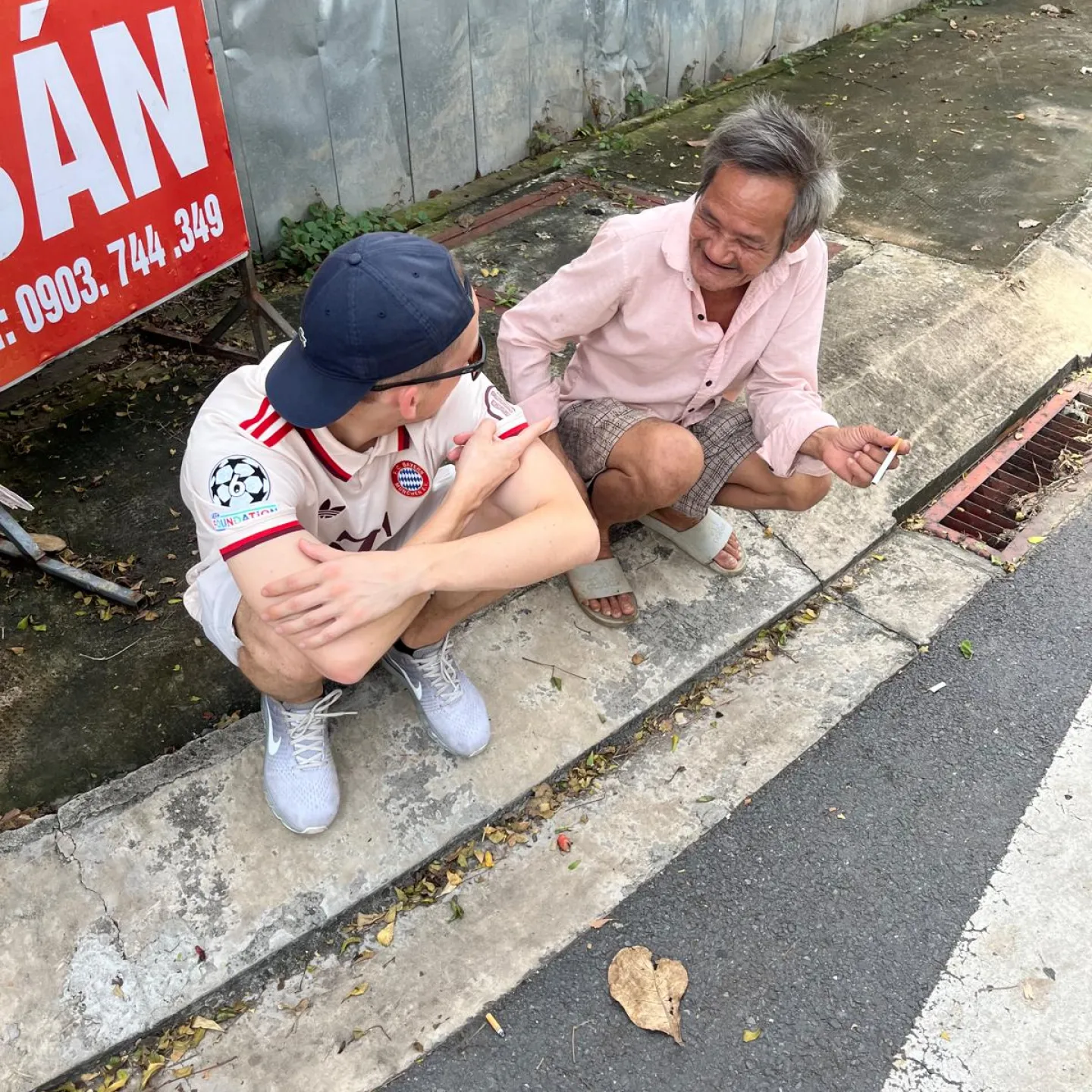 Der Autor zusammen mit einem Vietnamesen am Strassenrand sitzend