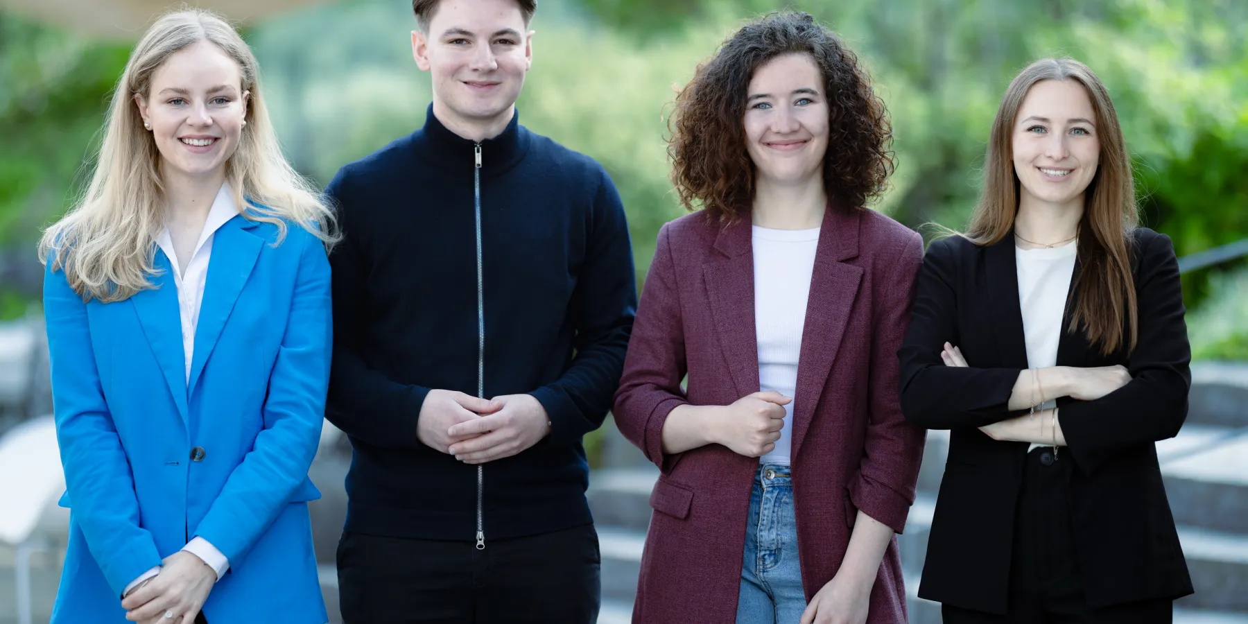 Vier Studierende der Universität Liechtenstein Bachelor BWL posieren gemeinsam im modernen Campusgebäude – Fokus auf studentische Vielfalt und Gemeinschaft.