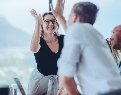 Freudiger High Five zwischen zwei Personen während eines erfolgreichen Business Meetings