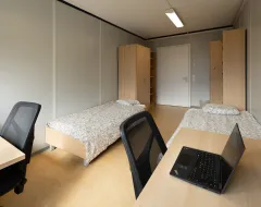 Doppelzimmer im Studierendenwohnheim der Universität Liechtenstein mit zwei Betten, Schreibtischen und Schränken.