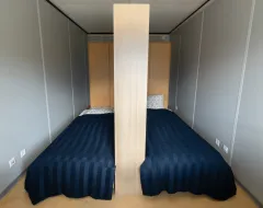 Zimmer mit zwei Einzelbetten, getrennt durch eine Regalwand, im Studierendenwohnheim der Universität Liechtenstein.