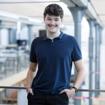 Student blaues T-Shirt im Campusgebäude lächelnd