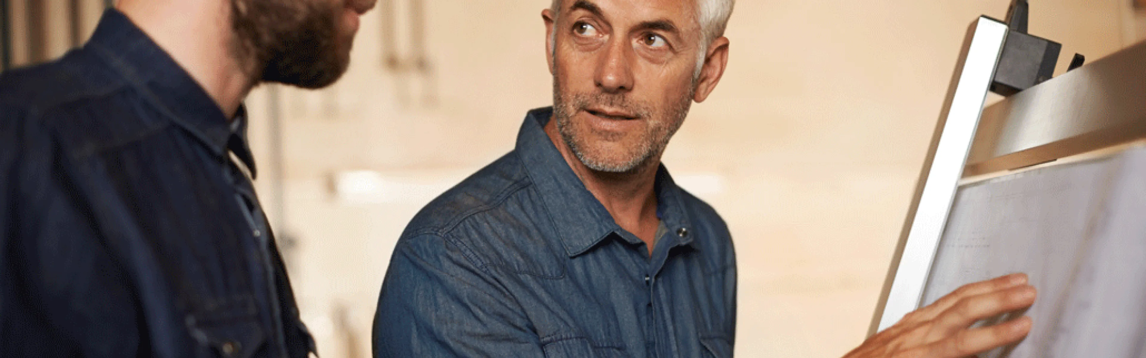 Zwei Männer betrachten gemeinsam einen Plan an einem Flipchart