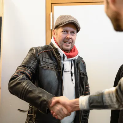 Alumnus gibt einem anderen Teilnehmer zur Begrüßung die Hand während einer Veranstaltung an der Universität Liechtenstein.