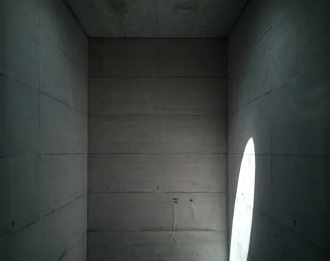 Minimalistischer Betonraum mit Oberlicht und Lichteinfall, der die schlichte Architektur betont.