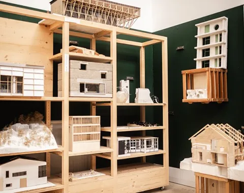 Architekturmodelle in einem Regal in einem Raum der Liechtenstein School of Architecture. Verschiedene Modelle aus Holz und anderen Materialien sind auf mehreren Ebenen ausgestellt.