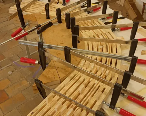 Ein Holzmodell eines Möbelstücks wird mit mehreren Schraubzwingen auf einem Tisch fixiert. Das Bild zeigt den handwerklichen Prozess der Studierenden während der «Maak Week» an der Universität Antwerpen.