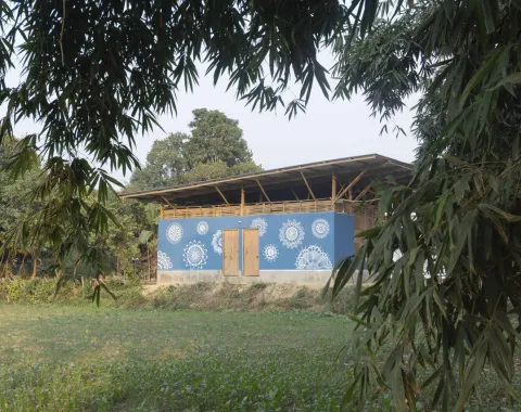 Ein nachhaltiges Gebäude mit blauer Fassade und weißen Mustern, umgeben von grüner Vegetation, symbolisiert umweltfreundliche Architektur.