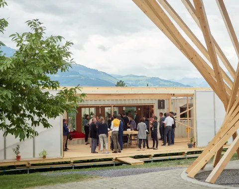 Aussenansicht des Base Camps, mit mehreren Menschen die davor stehen.