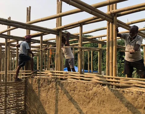 Arbeiter errichten eine Schule in Bahuarwa, Indien, mit Bambusgerüst und Lehmwänden. Das Projekt wird von der Universität Liechtenstein unterstützt.