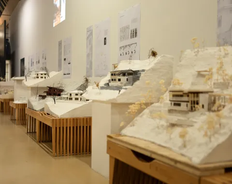 Mehrere Architekturmodelle in beige/weiss auf Holzbänken