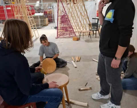 Mehrere Jugendliche in einer Halle arbeiten handwerklich