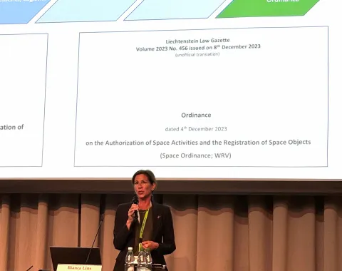 Referentin präsentiert juristische Inhalte zu Raumfahrtgesetzgebung vor Präsentationsfolie bei Fachsymposium