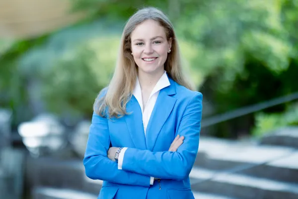 Studentin Bachelor BWL der Universität Liechtenstein im blauen Jacket lächelt in die Kamera – Campusaufnahme 