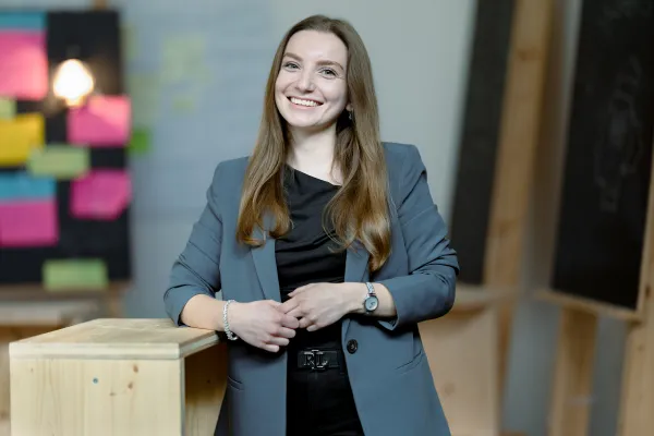 Studentin des Master Entrepreneurship, Innovation und Leadership der Universität Liechtenstein im blauen Blazer lächelt in die Kamera – Campusaufnahme in freundlicher Lernumgebung.