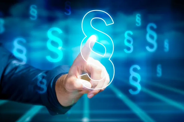 Person drückt auf ein digitales Paragrafzeichen vor einem leuchtend blauen Hintergrund mit rechtlichen Symbolen.