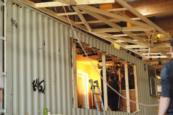 Grauer Schiffscontainer mit Holzkonstruktion, der sich im Umbau befindet