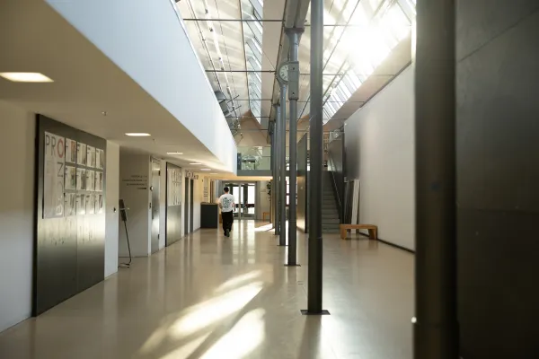Heller Flur mit Uhr, Sitzgelegenheiten und Zugang zu Hörsälen an der Universität Liechtenstein.