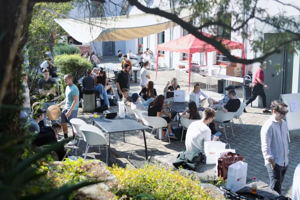 Campusleben im Innenhof der Universität Liechtenstein mit Gesprächen, Getränken und entspannter Atmosphäre.