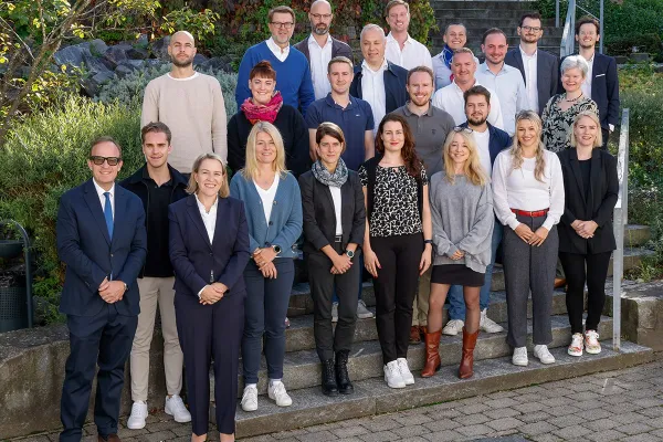 Gruppenfoto von Studierenden und Dozenten des Executive Master of Laws (LL.M.) im Gesellschafts-, Stiftungs- und Trustrecht an der Universität Liechtenstein. Die Gruppe steht auf einer Treppe im Freien, umgeben von grüner Vegetation.
