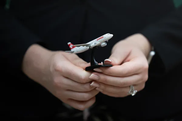 Hände halten Modellflugzeug der Fluggesellschaft SWISS.